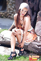 Sitting on log topless leaning forward long hair hand on knee wearing black high heels