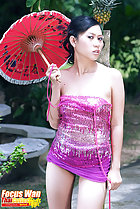 Focus Wan standing against tree holding red parasol